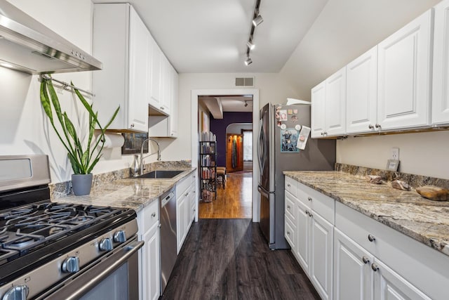 kitchen with wall chimney exhaust hood, arched walkways, visible vents, appliances with stainless steel finishes, and a sink