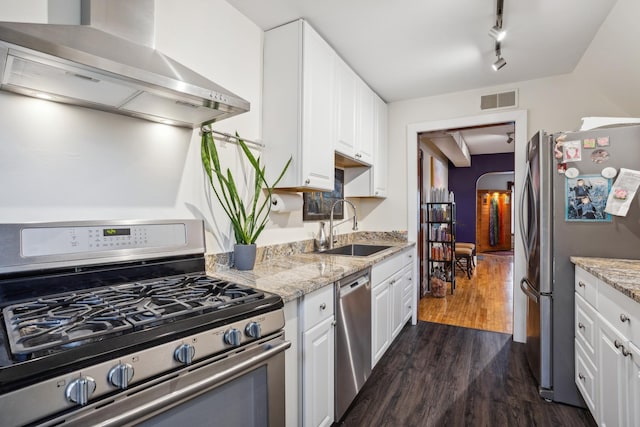kitchen featuring visible vents, wall chimney exhaust hood, a sink, appliances with stainless steel finishes, and dark wood-type flooring
