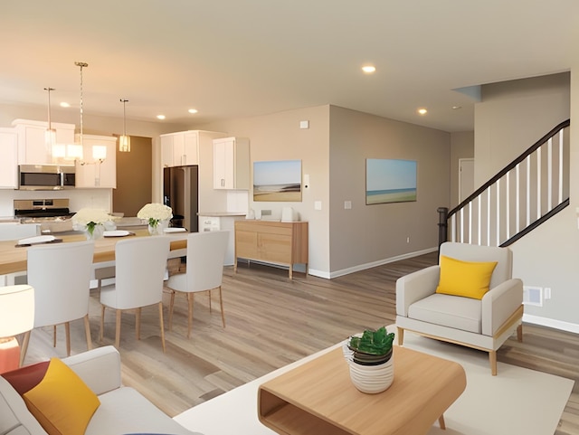 living area featuring light wood-type flooring, recessed lighting, baseboards, and stairs