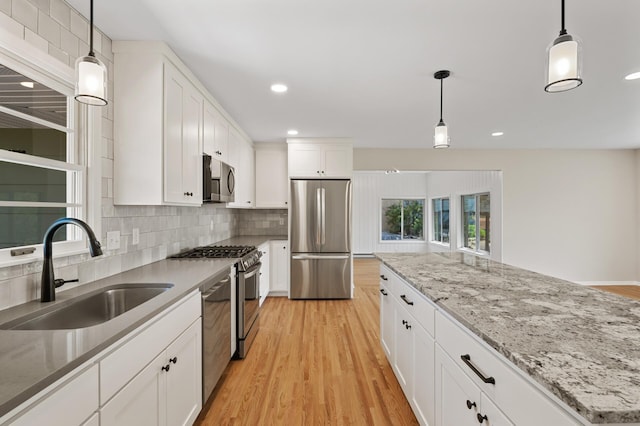 kitchen with stainless steel appliances, a sink, tasteful backsplash, recessed lighting, and light wood-style floors