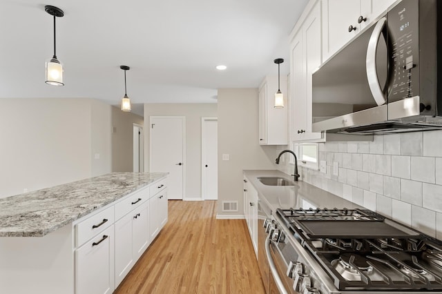 kitchen with stainless steel appliances, a sink, decorative backsplash, white cabinets, and recessed lighting
