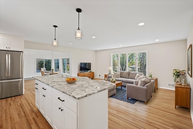 kitchen with stainless steel fridge, light wood-type flooring, white cabinetry, decorative light fixtures, and recessed lighting