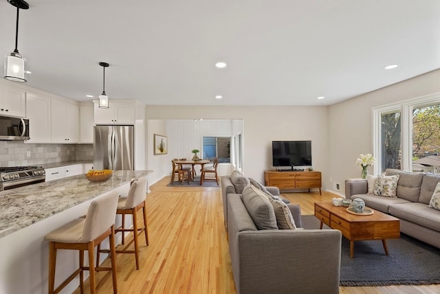 living area with light wood-type flooring and recessed lighting