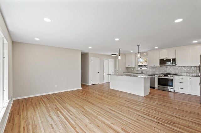 kitchen with stainless steel appliances, decorative backsplash, a kitchen island, recessed lighting, and white cabinets
