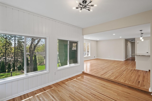 unfurnished living room with a chandelier and light wood finished floors