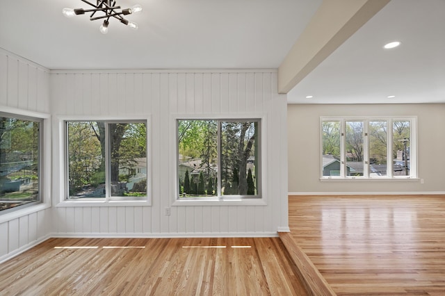 unfurnished living room featuring wood finished floors, a chandelier, baseboards, and recessed lighting
