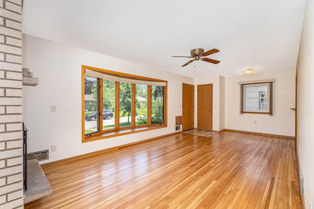 4926 Madison St NE, Columbia Heights, MN 55421 - unfurnished living room featuring light wood finished floors, healthy amount of natural light, ceiling fan, and a brick fireplace