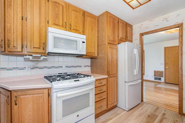 4926 Madison St NE, Columbia Heights, MN 55421 - kitchen with white appliances, light wood finished floors, decorative backsplash, and light countertops