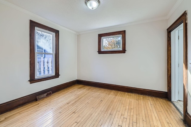 unfurnished room with light wood-style floors, crown molding, baseboards, and visible vents