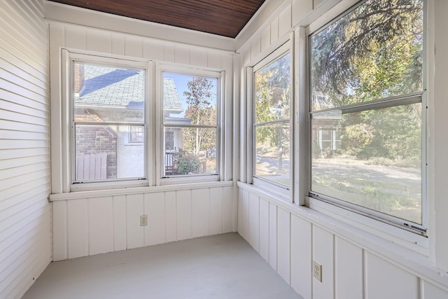 unfurnished sunroom featuring a decorative wall, wooden walls, and a wealth of natural light
