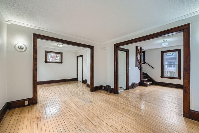 interior space with stairway, light wood-style flooring, baseboards, and crown molding