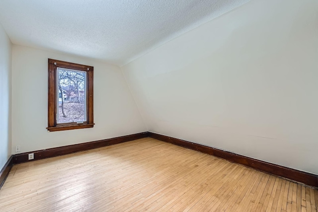 spare room featuring hardwood / wood-style floors, baseboards, and a textured ceiling
