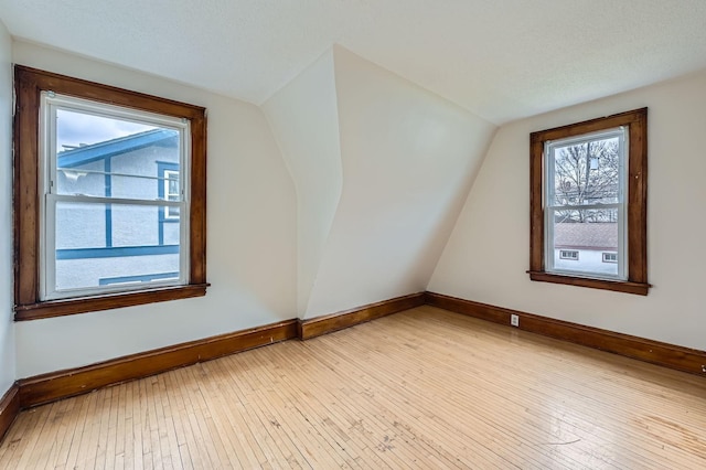additional living space featuring vaulted ceiling, baseboards, and hardwood / wood-style floors