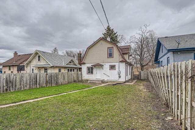 back of property featuring a gambrel roof, a fenced backyard, and a yard