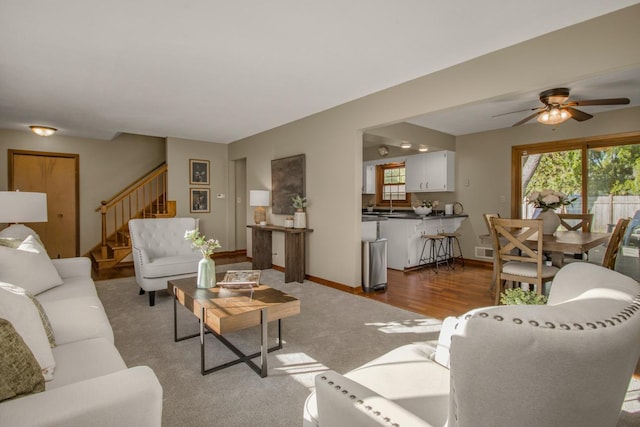 living area featuring stairs, ceiling fan, carpet, and baseboards