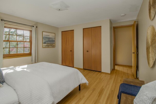 bedroom with multiple closets and light wood-type flooring