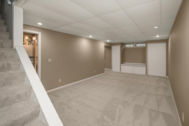 finished below grade area featuring carpet flooring, stairway, recessed lighting, a drop ceiling, and baseboards