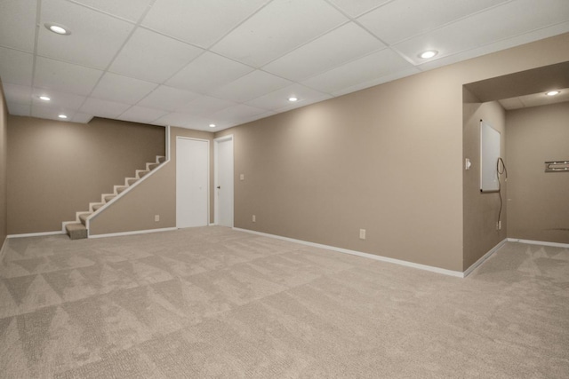 finished below grade area with light carpet, baseboards, recessed lighting, stairs, and a paneled ceiling