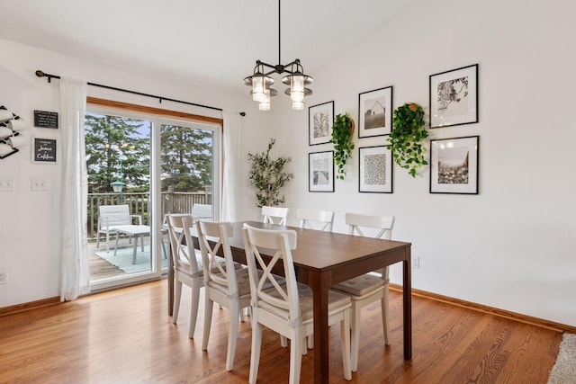 dining area featuring light wood-style floors, baseboards, and a chandelier