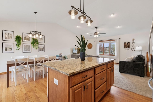 kitchen featuring lofted ceiling, open floor plan, light wood-style flooring, ceiling fan, and a kitchen island