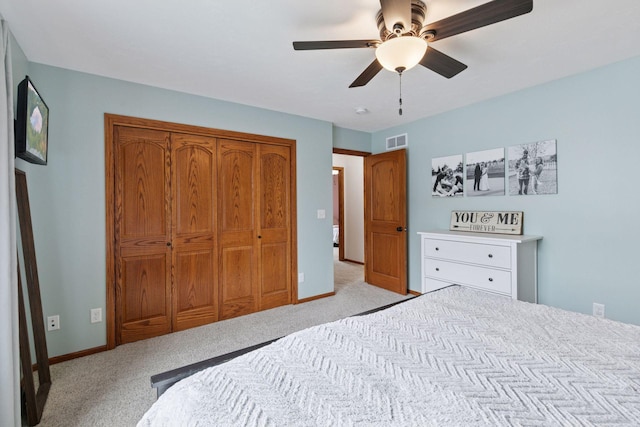 bedroom featuring light carpet, ceiling fan, a closet, and baseboards
