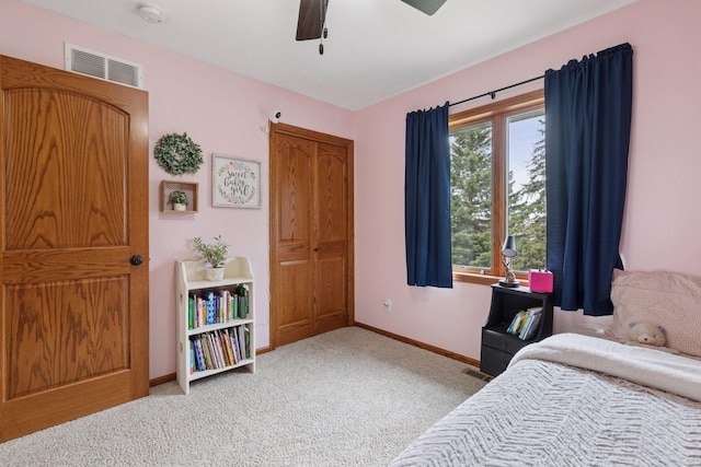 bedroom featuring light colored carpet, baseboards, ceiling fan, and a closet