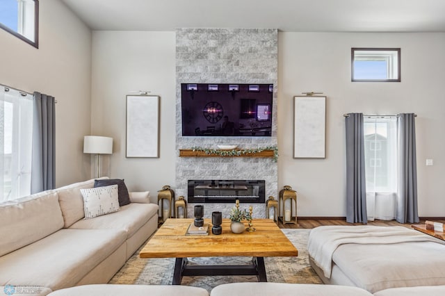 living room with a fireplace, baseboards, and wood finished floors