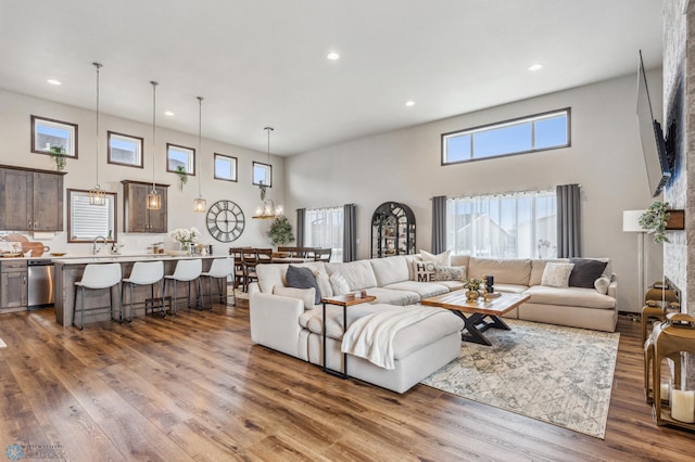living room with dark wood-type flooring, a high ceiling, a notable chandelier, and recessed lighting
