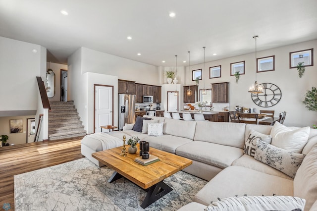 living room featuring recessed lighting, stairway, an inviting chandelier, and wood finished floors