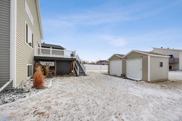 yard covered in snow with an outdoor structure, stairway, a deck, fence, and a storage unit