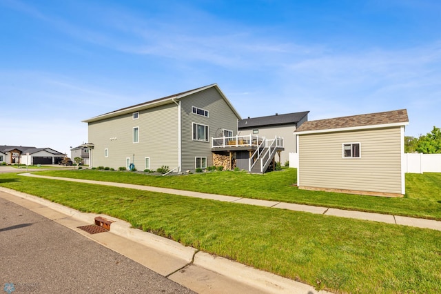 view of home's exterior with an outbuilding, a deck, stairway, and a lawn