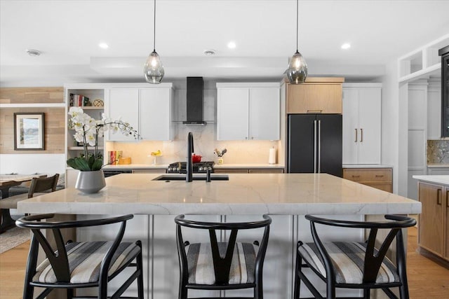 2041 Oak St, Lake City, MN 55041 - kitchen with tasteful backsplash, light stone counters, an island with sink, wall chimney exhaust hood, and freestanding refrigerator