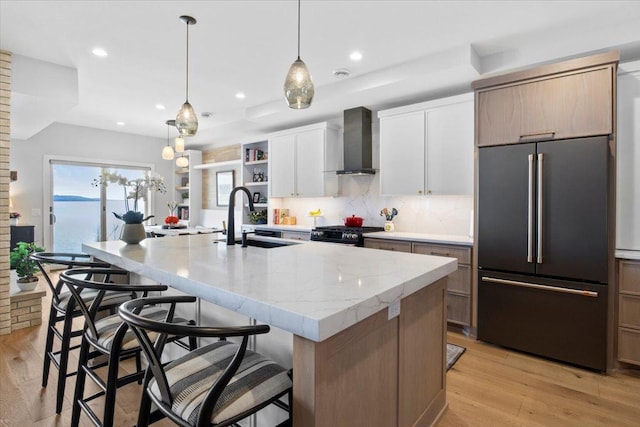 2041 Oak St, Lake City, MN 55041 - kitchen featuring high end refrigerator, wall chimney range hood, a sink, decorative backsplash, and a center island with sink