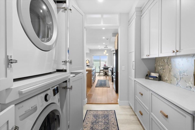 2041 Oak St, Lake City, MN 55041 - washroom featuring a sink, cabinet space, light wood-style flooring, stacked washer and clothes dryer, and recessed lighting