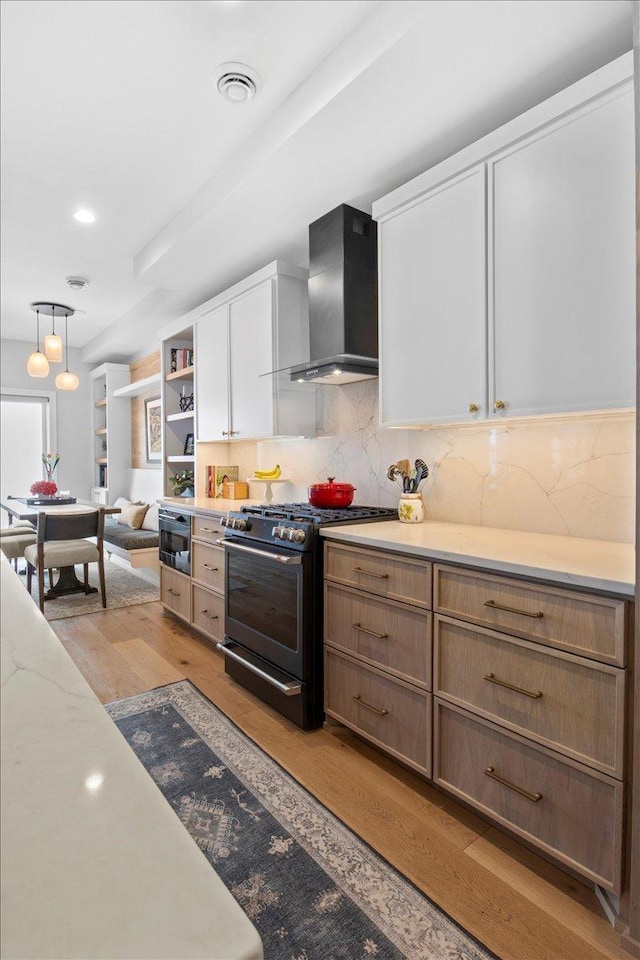 2041 Oak St, Lake City, MN 55041 - kitchen with wall chimney range hood, tasteful backsplash, light wood-type flooring, white cabinetry, and gas stove