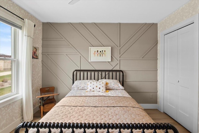 2041 Oak St, Lake City, MN 55041 - bedroom featuring wallpapered walls, wood finished floors, a decorative wall, a closet, and baseboards