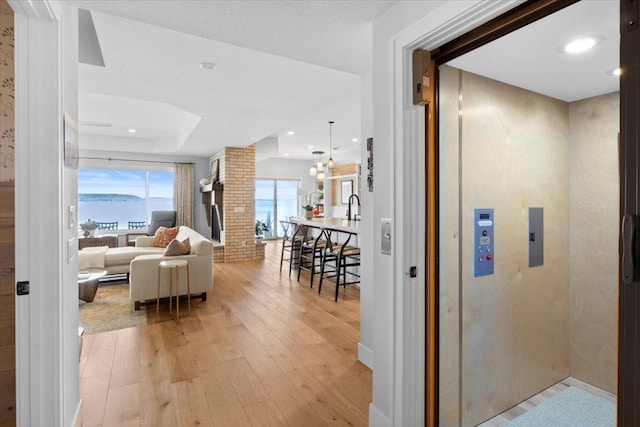 2041 Oak St, Lake City, MN 55041 - hall featuring light wood-style flooring, elevator, recessed lighting, a chandelier, and a tray ceiling