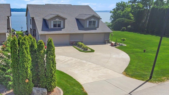 2041 Oak St, Lake City, MN 55041 - view of front of house with an attached garage, driveway, a front lawn, a shingled roof, and a water view