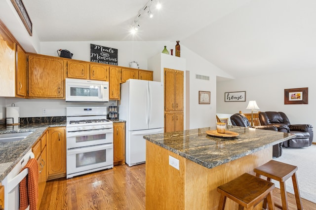 kitchen featuring lofted ceiling, track lighting, visible vents, white appliances, and open floor plan