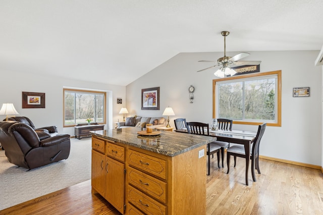 kitchen featuring light wood-style flooring, ceiling fan, a kitchen island, open floor plan, and vaulted ceiling
