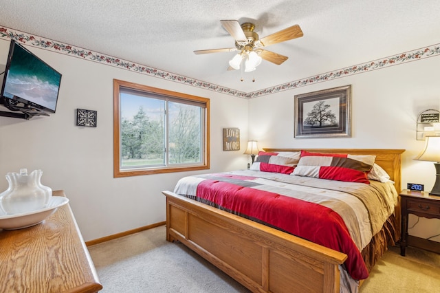 bedroom featuring a textured ceiling, ceiling fan, light carpet, and baseboards