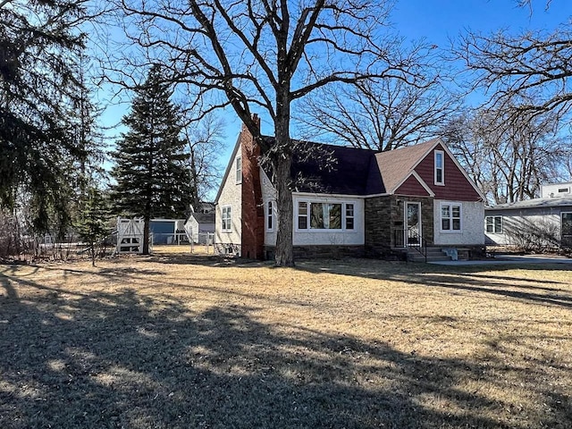 305 Kneale Ave N, Thief River Falls, MN 56701 - view of front of property with a chimney, stone siding, and a front lawn