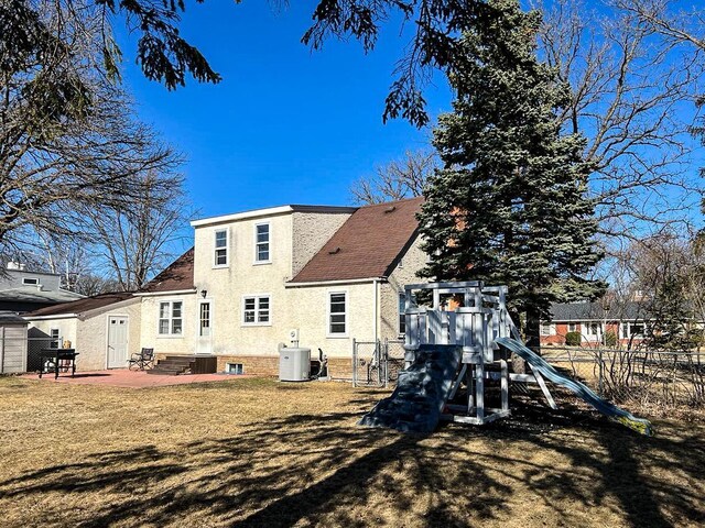 305 Kneale Ave N, Thief River Falls, MN 56701 - back of house with a patio area, fence, a playground, and stucco siding