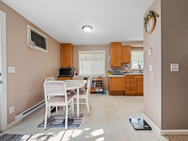 kitchen featuring light floors, black microwave, baseboard heating, light countertops, and baseboards