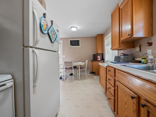 kitchen featuring white appliances, brown cabinets, light countertops, and light floors