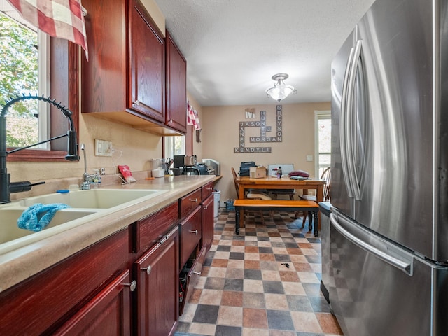 kitchen featuring a sink, dark brown cabinets, light countertops, and freestanding refrigerator