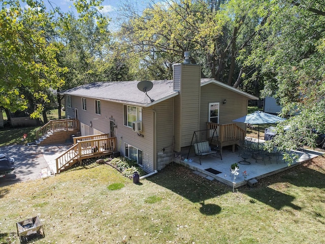 rear view of house featuring a patio, a deck, a chimney, and a lawn