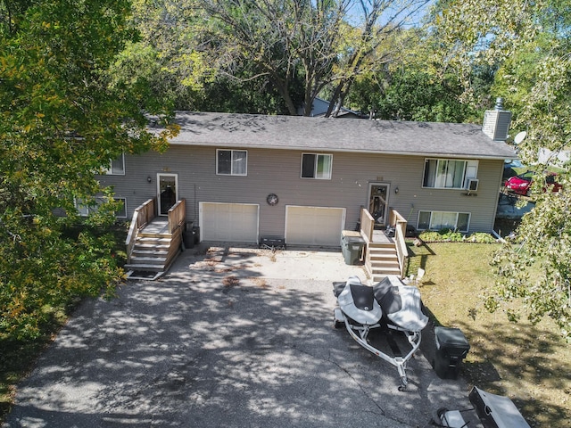 rear view of house featuring a chimney, a garage, and aphalt driveway