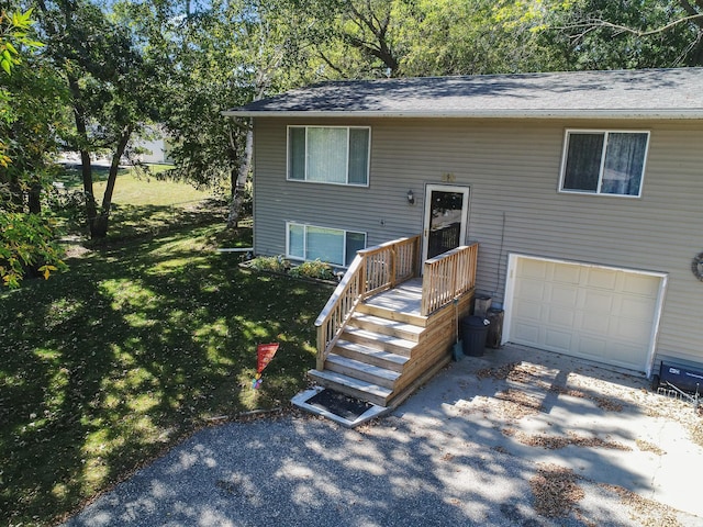 split foyer home featuring an attached garage, a front lawn, and roof with shingles