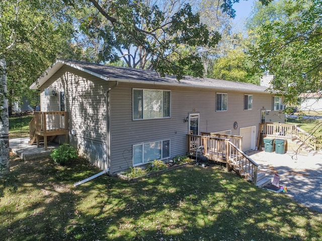 back of house with a garage, stairway, a chimney, and a lawn